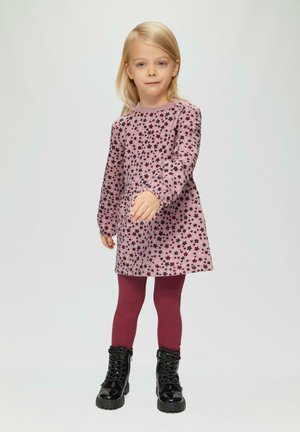 Robe rose à manches longues avec un motif floral noir, associée à des leggings bordeaux et des bottes à lacets noires brillantes. Design simple et décontracté.