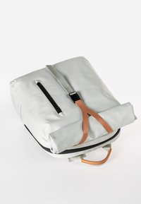 Grau farbener Rucksack mit rechteckiger Form, ausgestattet mit einem Ledergriff, einer Reißverschlusstasche und einem oberen Handgriff. Hergestellt aus einem glatten, strapazierfähigen Material.