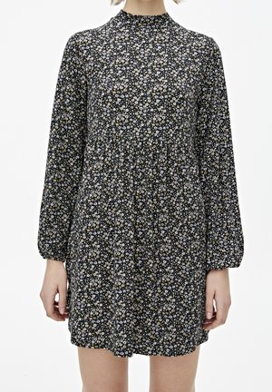 Robe noire à manches longues avec un col haut, ornée d'un motif floral en blanc, jaune et vert. Design fluide avec une taille cintrée.