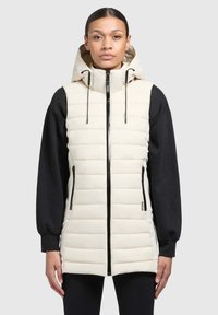 Padded Weste in Creme mit Kapuze, Reißverschluss und Seitentaschen. Mit schwarzen langen Ärmeln und elastischem Saum. Glatte Textur.