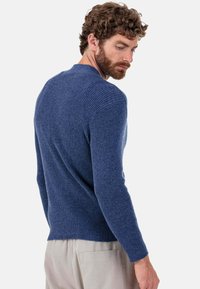 Blauer gerippter Strickpullover mit langen Ärmeln und Rundhalsausschnitt, mit figurbetontem Schnitt und strukturierter Stoffqualität. Sichtbare Rückennaht-Detail.