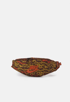 Sac banane Nike à motif camouflage marron et orange avec double fermeture éclair et sangle réglable sur fond blanc.