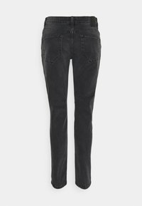 Jeans de denim negro con corte ajustado, que cuentan con dos bolsillos traseros, costuras discretas y una textura suave. Sin adornos visibles.