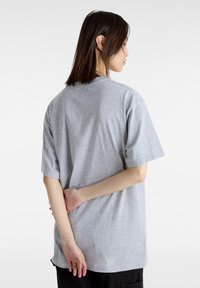 Camiseta de algodón gris de manga corta y corte relajado. La parte posterior presenta un diseño simple con un dobladillo recto y una textura suave.