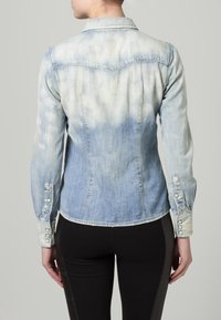 Giubbotto di jeans con gradiente blu chiaro e finitura sbiadita. Presenta maniche lunghe, polsini con bottone, cucitura dello yoke posteriore e design del colletto classico.