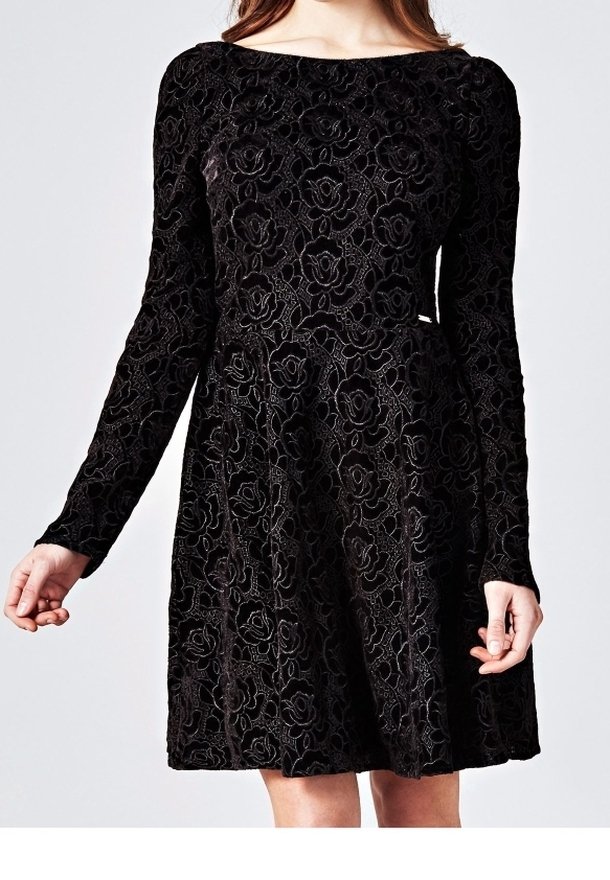 Svart sammetsklänning med långa ärmar. Har ett blommönstrat spetsmönster och en figurnära överdel som vidgar sig vid midjan.