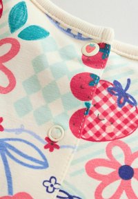 Bombažna obleka z barvitimi vzorci jagod, cvetov in listov. Zapiranje z zopetnimi gumbi z belo podlogo in finimi teksturami.