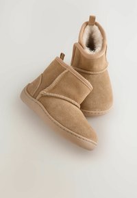 Wildleder-Ankle Boots in hellbraun mit weichem Fellfutter, abgerundeter Spitze, Rückenzuglasche und kontrastierenden Nähten an den Seiten.