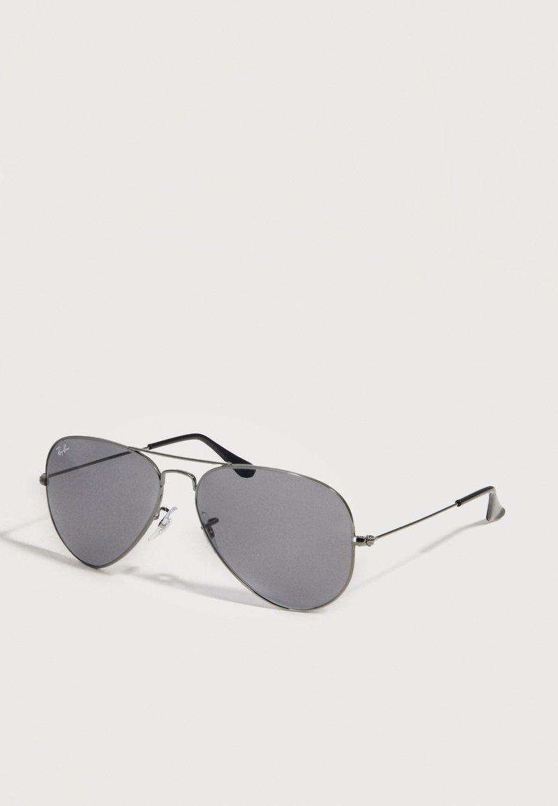 Γυαλιά ηλίου Ray-Ban aviator με λεπτό μεταλλικό πλαίσιο και σκουρόχρωνους γκρίζους φακούς σε ανοιχτό φόντο.