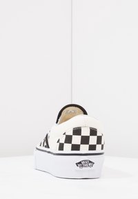 Zwart-wit geblokte slip-on sneaker met een witte rubberen zool en zwarte accenten. Het canvasmateriaal heeft een gevoerde kraag.