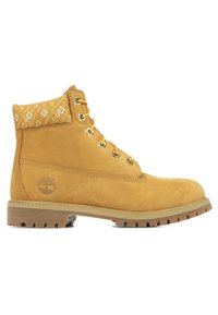 Botas de tobillo de ante marrón con un cuello de color beige con patrón, ojales dorados y suela de goma resistente con surcos profundos para mayor tracción.