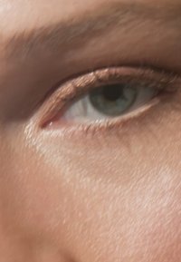 Nahaufnahme eines menschlichen Auges mit einer türkisfarbenen Iris, definierten Wimpern und metallic-braunem Eyeliner. Die Hauttextur wirkt glatt mit subtilen Highlights.