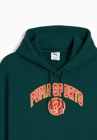 Sudadera verde oscura con un gran gráfico multicolor de "PUMA SPORTS" en el frente. Incluye capucha con cordones y una textura suave.