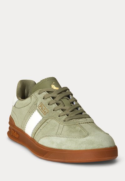 Žalios spalvos zomšiniai Polo sportbačiai su baltu šoniniu dryžu, ruda gumine pado danga, su nėrinių užsegimu ir aukso spalvos Polo logotipu ant liežuvio ir šono.