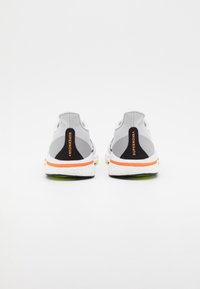 Scarpe da corsa in rete grigia con accenti neri e etichetta "SUPERNOVA+". Presentano un'intersuola bianca con dettagli arancioni e verdi. Design atletico standard.