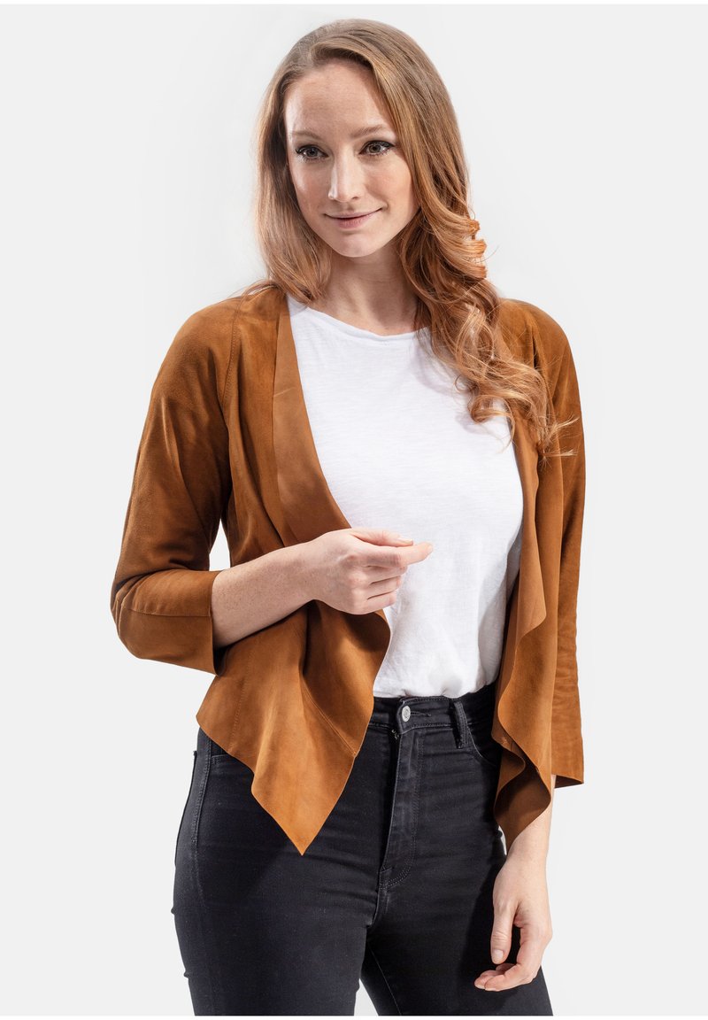 Bruine suede cardigan met open voorkant en driekwart mouwen, gelaagd ontwerp, gedragen over een wit T-shirt en zwarte jeans.