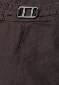 Pantalon en tissu marron avec une boucle rectangulaire en métal fixant une ceinture en tissu réglable à la taille.