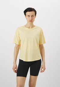Gul kortermet t-skjorte med avslappet passform. Mykt, lett stoff med en subtil tekstur. Pair med svarte, tettsittende shorts.