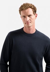 Donkerblauwe geribde trui met een ronde hals en een gestructureerde stof, ontworpen voor een nauwsluitende uitstraling met lange mouwen.