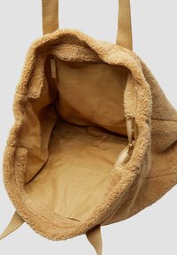 Torbka z miękkiego pluszu w odcieniu beżowym, o teksturowanej powierzchni. Posiada nieuszczypliwy kształt, wewnętrzną kieszeń zapinaną na suwak oraz gładką satynową podszewkę.