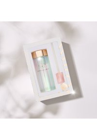 Przezroczysta, iryzująca butelka na wodę ze złotą pokrywką i różowym akcentem kryształowym. Zawiera słomkę, zapakowana w dekoracyjne pudełko z geometrycznymi wzorami.