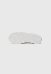 White sneaker sole with circular and textured patterns, featuring logo detail in the center. Made of rubber material, flat design.