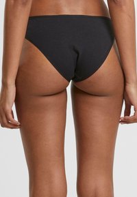 Svart bikiniunderdel i mjukt tyg med hög skärning och minimal täckning. Har en slät midja och sömlös design.