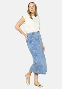 Svetloblue jeans krilo z vzorcem leoparda, visoko pasovo zasnovo in ravno obliko. Usklajeno s bež topom in zlatimi balerinkami.
