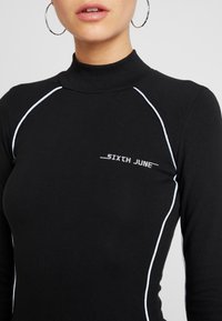 Czarny longsleeve z wysokim kołnierzem, z białym wykończeniem przy szwach i logo 'SIXTH JUNE' na piersi w prostym kroju.