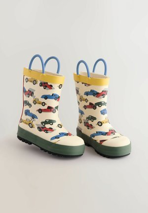 Gummiregenstiefel mit einer cremefarbenen Basis, bunten Auto-Mustern, gelbem Rand, blauen Griffen und strukturierten grünen Sohlen für zusätzlichen Halt.