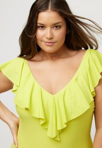 Maillot de bain jaune avec des manches volantées et un décolleté en V profond. Texture lisse avec un design ajusté, mettant en valeur le décolleté et les épaules.
