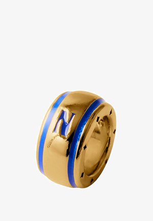 Anillo de color dorado con rayas de esmalte azul, que presenta una prominente letra "N" en la superficie. Acabado liso y pulido con bordes redondeados.