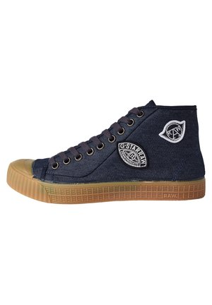 Tummansininen korkeavartinen denim-tennari, jossa ruskea kumipohja, nauhat ja kaksi valko-mustaa G-Star RAW -logokangaspalaa sivulla.