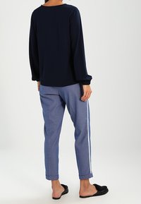 Navy long-sleeve top, soft fabric; paired with light blue patterned pants with a white side stripe; worn with black slip-on shoes.
