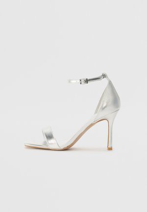 Srebrne sandały na wysokim obcasie o metalicznym wykończeniu, z eleganckim designem, paskiem na kostce i minimalistycznymi paskami. Gładka faktura.
