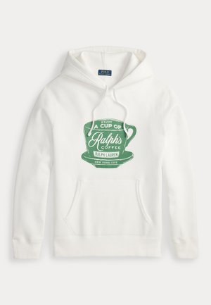 Deux personnes se tiennent debout, portant des sweats à capuche blancs avec des logos de tasses de café verts, des jeans bleus et des chaussures décontractées ; l'une porte une casquette verte et des lunettes.