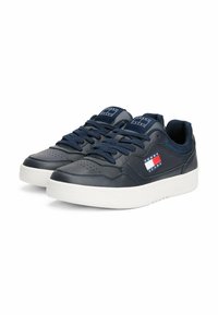 Navy leather sneakers with white sole and perforated toe. Features blue laces and a logo patch in red, white, and blue on the side.