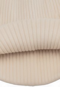 Primo piano di un tessuto a maglia beige piegato con linee verticali testurizzate.