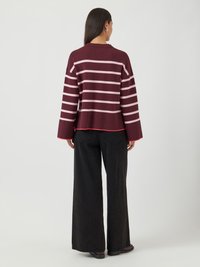 Maglione a righe borgogna con maniche ampie, texture a costine e design corto, abbinato a pantaloni a gamba larga neri a vita alta.