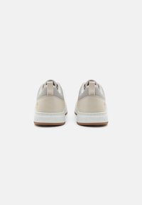 Elegante, niedrige Sneaker in hellbeige mit grauen Akzenten, aus einer Kombination von strukturiertem Wildleder und glattem Leder, und einer weißen Gummisohle.