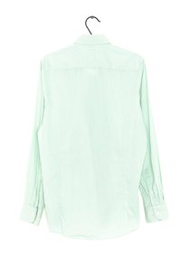 Camicia a maniche lunghe verde chiaro con un sottile motivo a pois, con polsini a bottone e colletto classico, appesa a un gancio nero.