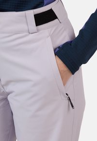 Jasnoszare spodnie o gładkiej fakturze, z boczną kieszenią na zamek błyskawiczny, paskiem na rzep oraz wbudowaną kieszenią na rękę.