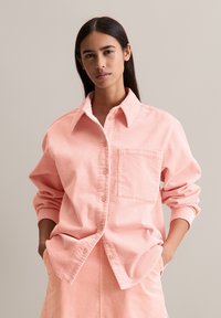Perzikkleurig corduroy overhemd met knopen, een kraag, lange mouwen en een borstzak. Heeft een verticale ribbeltjesstructuur en een ontspannen pasvorm.