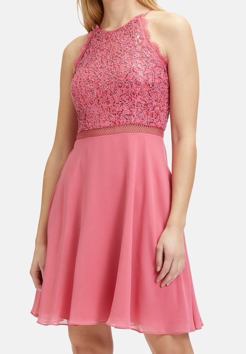 Pink dress with lace detailing on the bodice, a fitted waist, and a flared chiffon skirt. Features thin straps and a textured pattern.