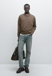 Brown long-sleeve polo, light blue straight-leg jeans, dark brown shoes, and a brown shoulder bag, set against a plain backdrop.