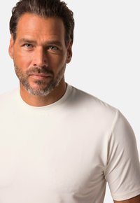 Hvid kortærmet T-shirt med rund hals, lavet af glat stof. Har et tætsiddende design og en subtil tekstur på overfladen.