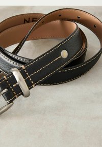 Cintura in pelle nera con fibbia in metallo argentato, presenta cuciture beige e un accento a logo rotondo. Il lato interno è liscio e di colore marrone chiaro.