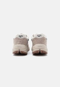 Beige tenisky s texturovanou, huňatou patou a tmavými akcenty. Obsahují logo "HI-TEC" a podrážku Vibram pro lepší přilnavost.