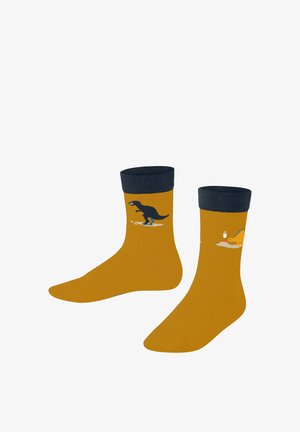 Des chaussettes jaunes présentent des motifs de dinosaures ludiques : un T-rex noir surfe et un dinosaure jaune avec une bougie. Des poignets côtelés bleu marine complètent le look.