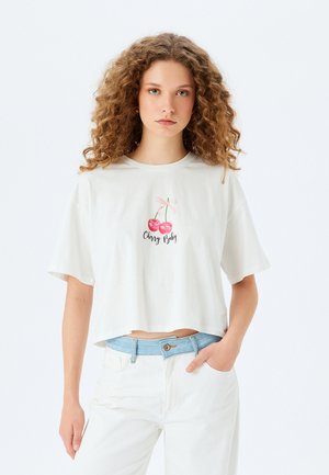 Hvid cropped t-shirt lavet af blødt stof, med et grafisk motiv af to kirsebær med en lyserød sløjfe og teksten "Cherry Baby" i sort.